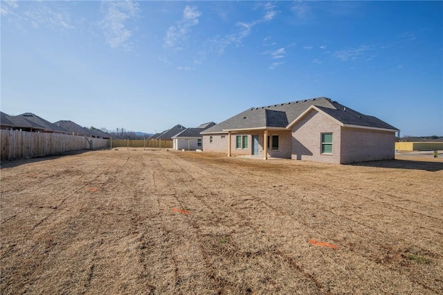 back of house featuring brick siding and fence