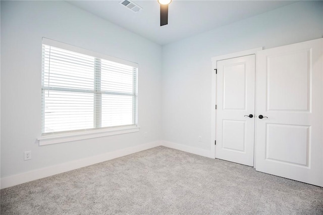 carpeted spare room featuring visible vents, ceiling fan, and baseboards