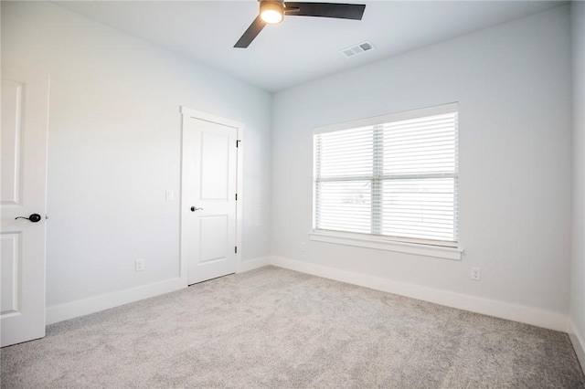 carpeted spare room featuring ceiling fan, visible vents, and baseboards