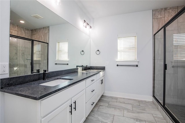 bathroom with a sink, a shower stall, baseboards, and double vanity