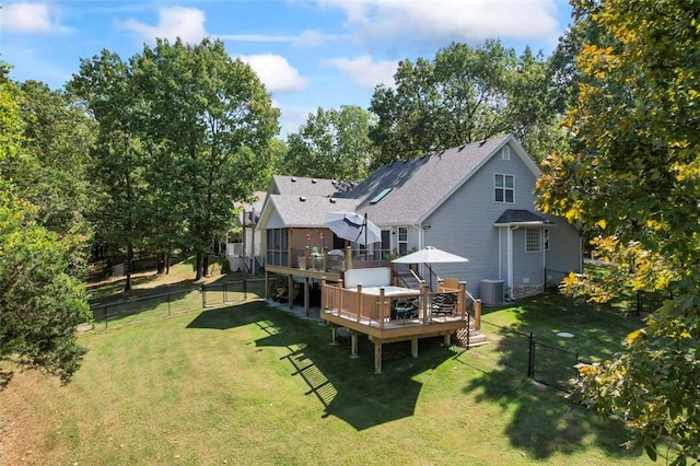 back of property featuring a lawn, a wooden deck, and central AC