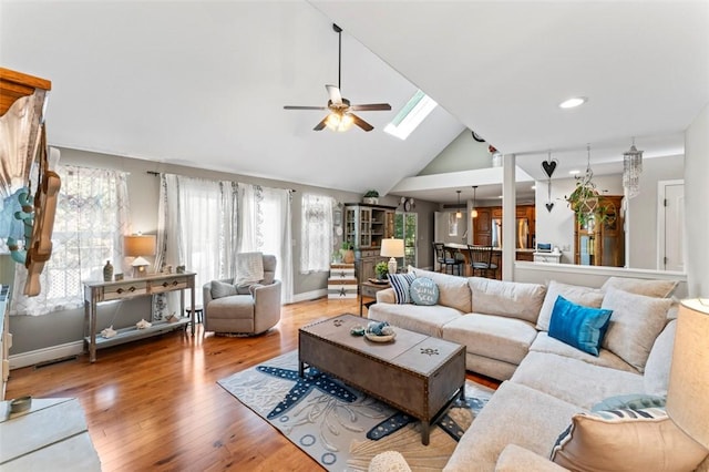 living room featuring hardwood / wood-style floors, ceiling fan, high vaulted ceiling, and a skylight