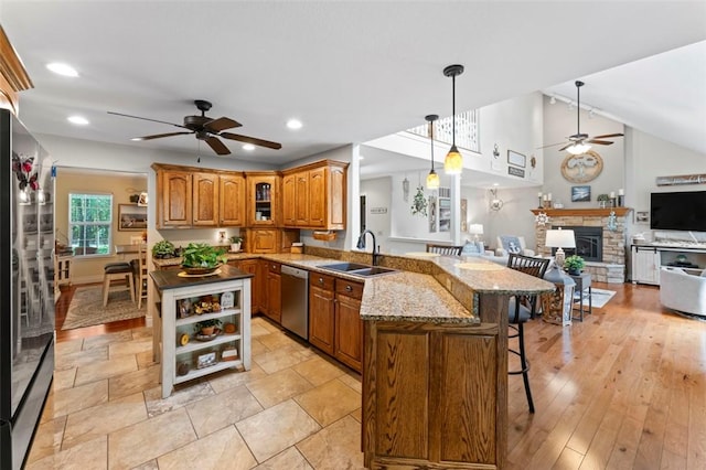 kitchen with a kitchen breakfast bar, sink, hanging light fixtures, kitchen peninsula, and stainless steel appliances