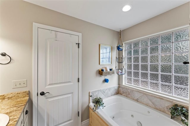 bathroom with vanity, tiled bath, and plenty of natural light