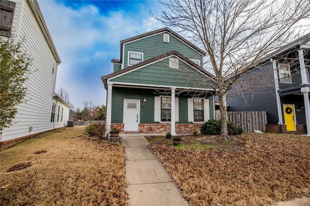 view of front of house with a porch, fence, brick siding, and central AC