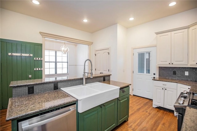 kitchen featuring white cabinetry, sink, light hardwood / wood-style floors, a kitchen island with sink, and appliances with stainless steel finishes