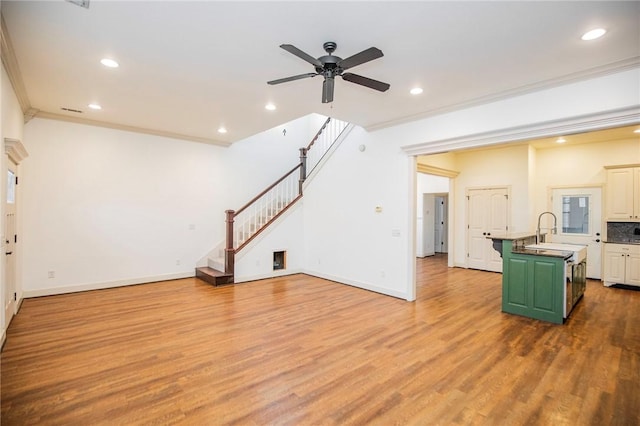 kitchen with a center island with sink, ceiling fan, ornamental molding, and sink