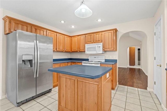 kitchen with a center island, white appliances, hanging light fixtures, and light tile patterned floors