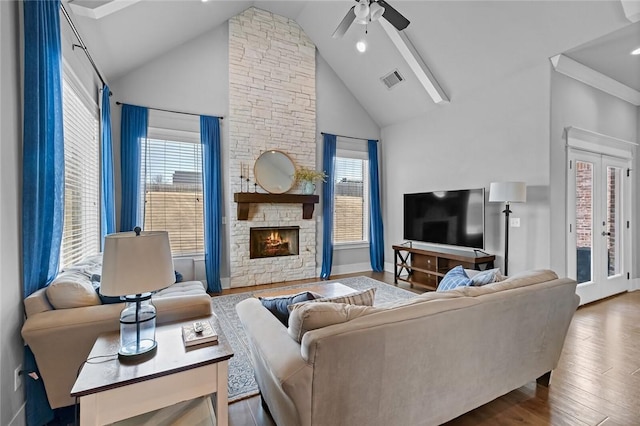 living room featuring a stone fireplace, ceiling fan, high vaulted ceiling, and hardwood / wood-style flooring