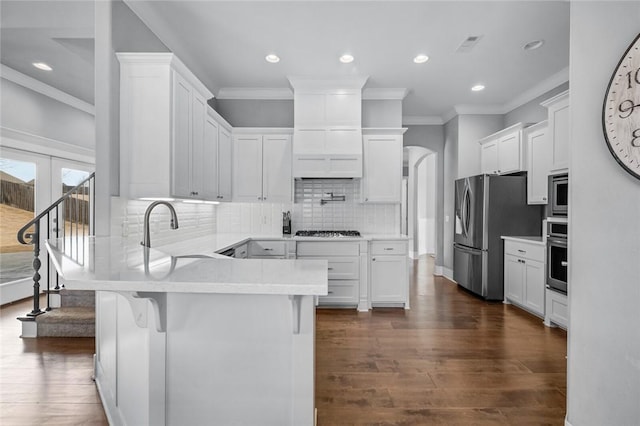 kitchen featuring dark wood-type flooring, sink, appliances with stainless steel finishes, white cabinetry, and a breakfast bar area