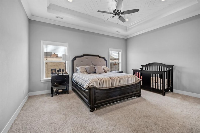 carpeted bedroom with a raised ceiling, multiple windows, ceiling fan, and ornamental molding