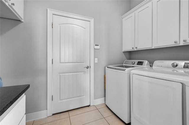 laundry room featuring cabinets, light tile patterned floors, and washer and dryer