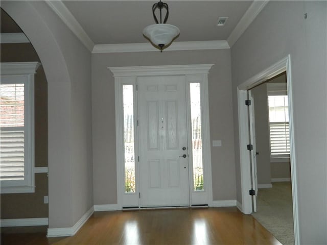 foyer with wood-type flooring and crown molding