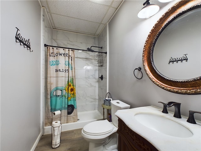 bathroom with a paneled ceiling, walk in shower, vanity, hardwood / wood-style floors, and toilet