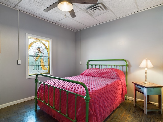 bedroom with dark hardwood / wood-style flooring, a paneled ceiling, and ceiling fan