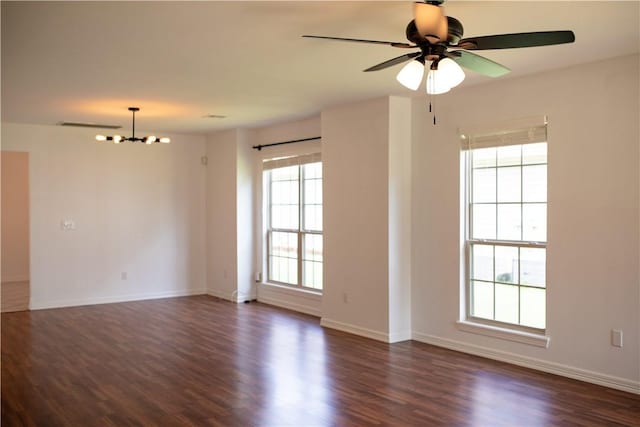 spare room featuring dark wood-style floors, ceiling fan with notable chandelier, and baseboards