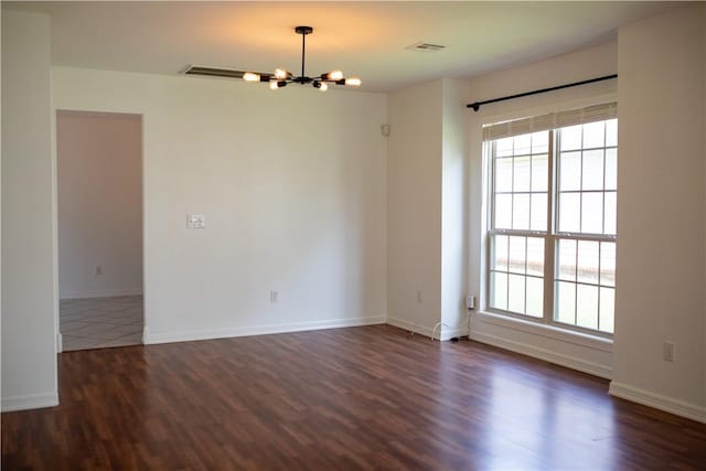 empty room with a notable chandelier, baseboards, dark wood-style flooring, and a wealth of natural light