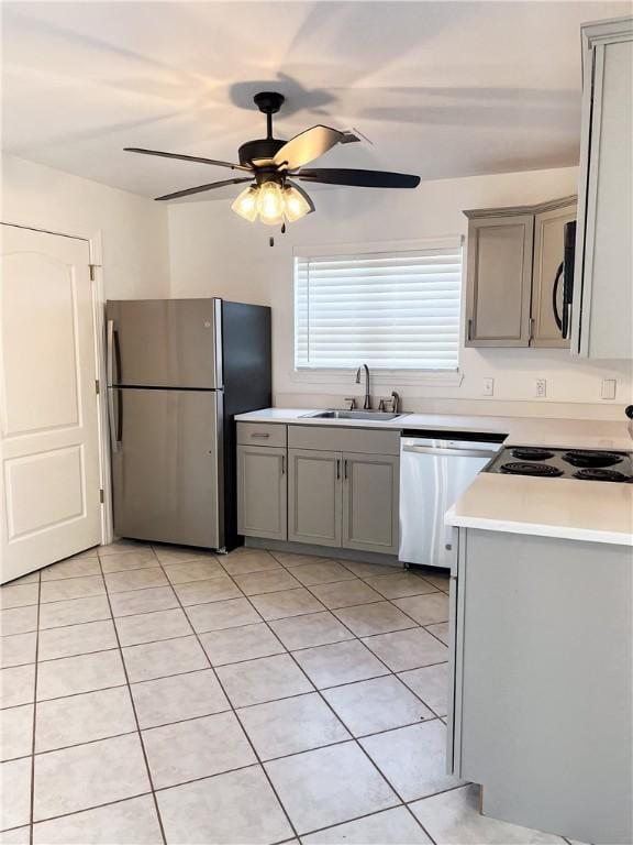 kitchen featuring stainless steel appliances, gray cabinets, light countertops, and a sink