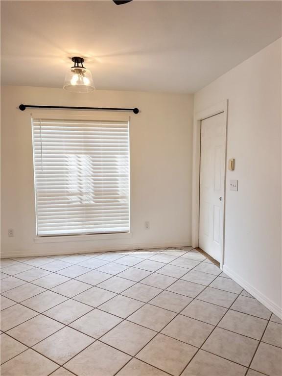 unfurnished room featuring a healthy amount of sunlight, light tile patterned floors, and baseboards