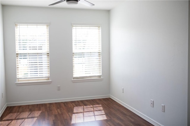 unfurnished room featuring dark wood-style flooring, ceiling fan, and baseboards