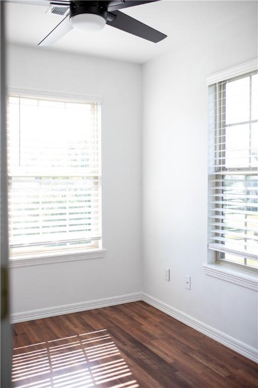 spare room featuring dark wood finished floors, a ceiling fan, and baseboards