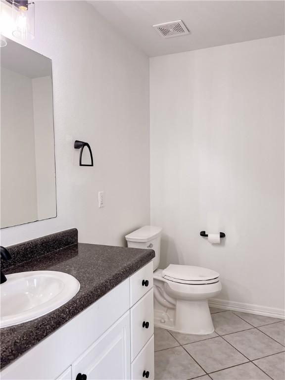 half bath featuring visible vents, baseboards, toilet, tile patterned flooring, and vanity