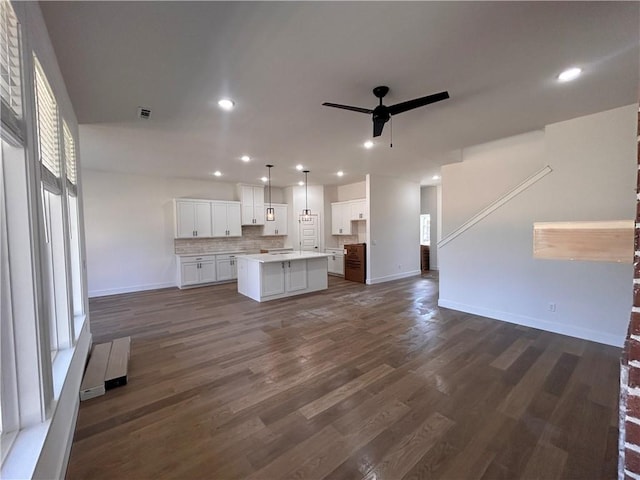 unfurnished living room with plenty of natural light, ceiling fan, and dark wood-type flooring