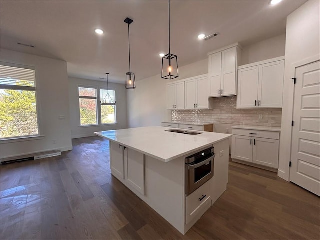 kitchen with pendant lighting, a center island, backsplash, white cabinets, and oven