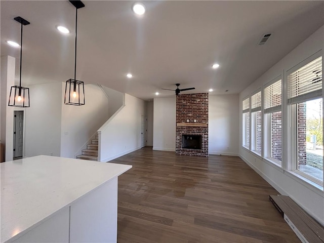 living room with ceiling fan, dark hardwood / wood-style flooring, a baseboard heating unit, and a brick fireplace