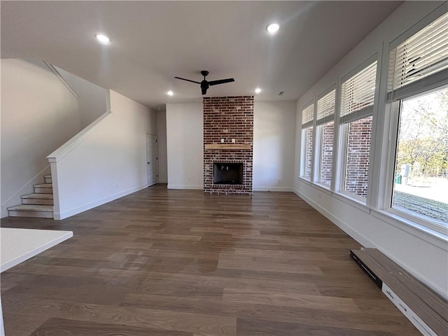 unfurnished living room featuring dark hardwood / wood-style floors, a brick fireplace, and ceiling fan