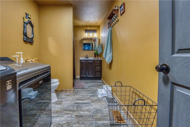 bathroom with toilet, washer / dryer, wood-type flooring, and vanity