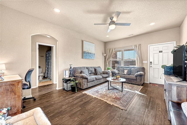 living room featuring dark wood-type flooring, a textured ceiling, and ceiling fan