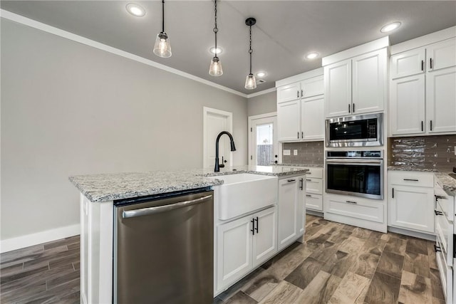 kitchen featuring white cabinetry, a center island with sink, pendant lighting, and appliances with stainless steel finishes