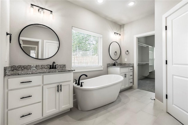 bathroom with tile patterned floors, vanity, and a washtub