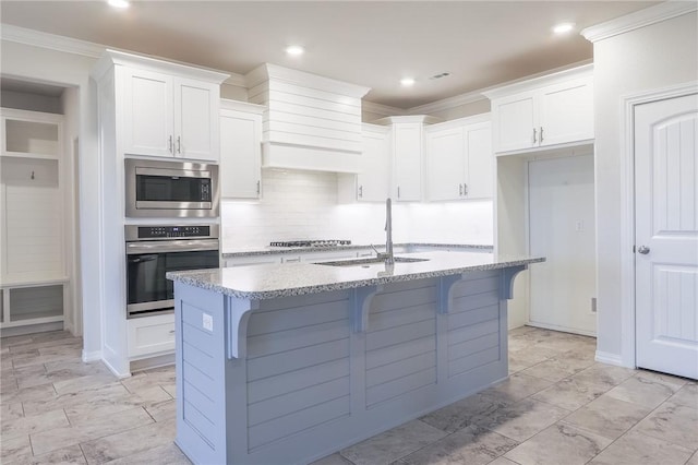 kitchen featuring stainless steel appliances, white cabinetry, a kitchen island with sink, and sink