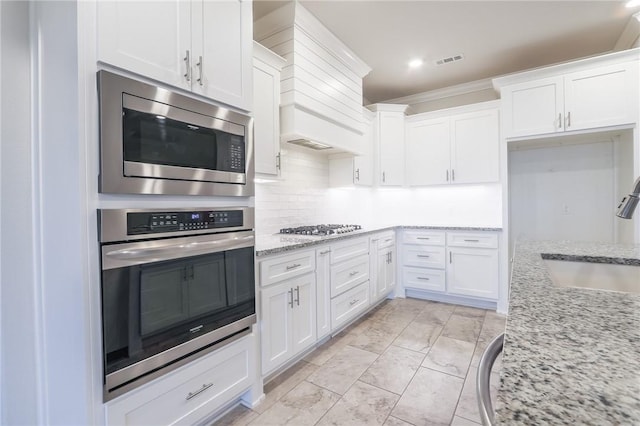 kitchen featuring white cabinets, stainless steel appliances, light stone counters, and sink