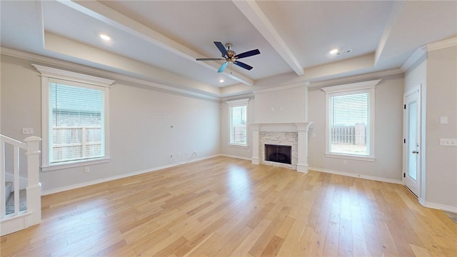 unfurnished living room featuring a stone fireplace, ceiling fan, plenty of natural light, and light wood-type flooring