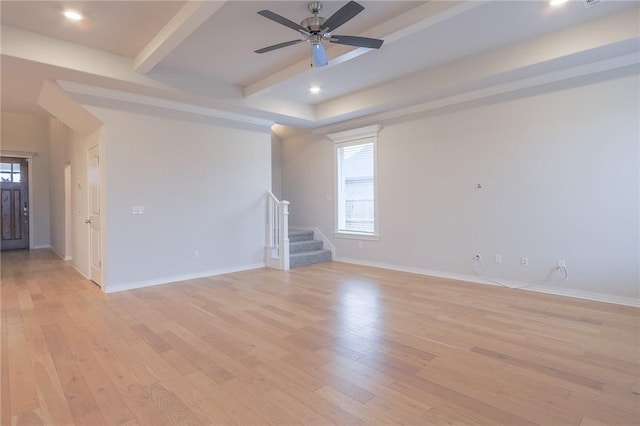 empty room with beamed ceiling, light hardwood / wood-style floors, and ceiling fan