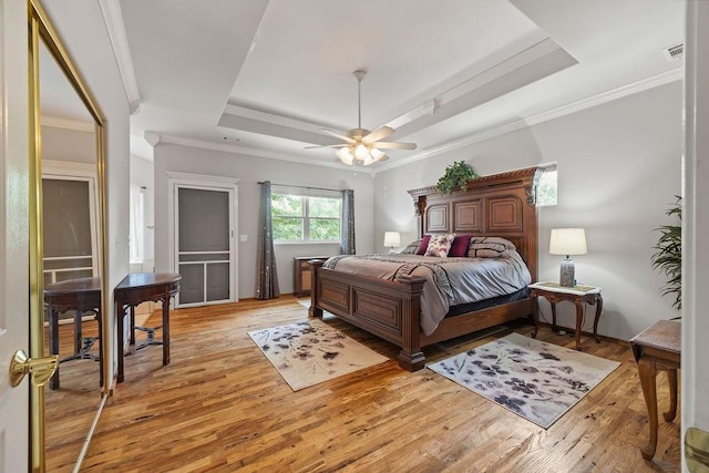 bedroom featuring light wood finished floors, ceiling fan, a tray ceiling, and crown molding