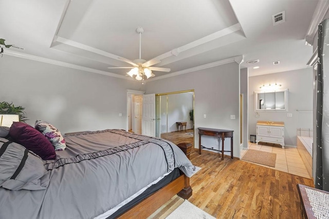 bedroom featuring wood finished floors, a raised ceiling, visible vents, and crown molding