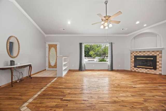 unfurnished living room featuring crown molding, baseboards, wood finished floors, and a tile fireplace