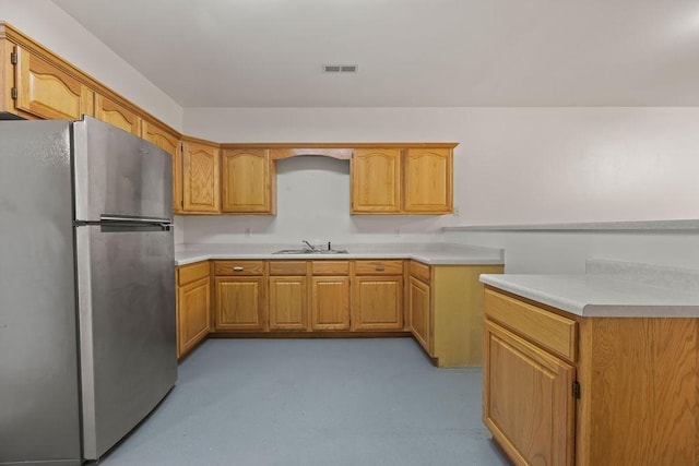 kitchen with visible vents, light countertops, a sink, and freestanding refrigerator