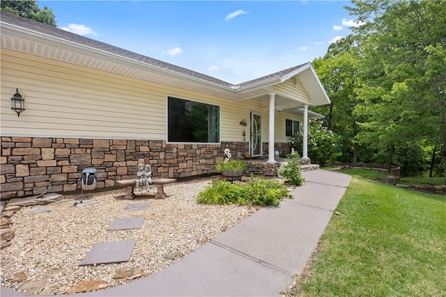 view of exterior entry featuring stone siding and a lawn