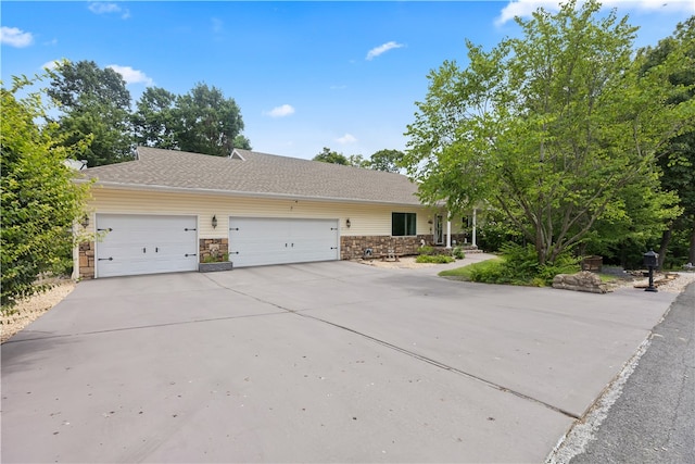 view of front of property featuring a garage, driveway, and stone siding