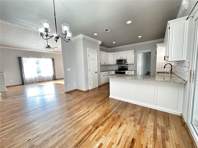 kitchen with visible vents, appliances with stainless steel finishes, open floor plan, a sink, and a peninsula