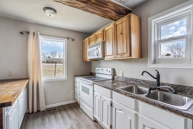 kitchen with white appliances, white cabinets, sink, light wood-type flooring, and a textured ceiling