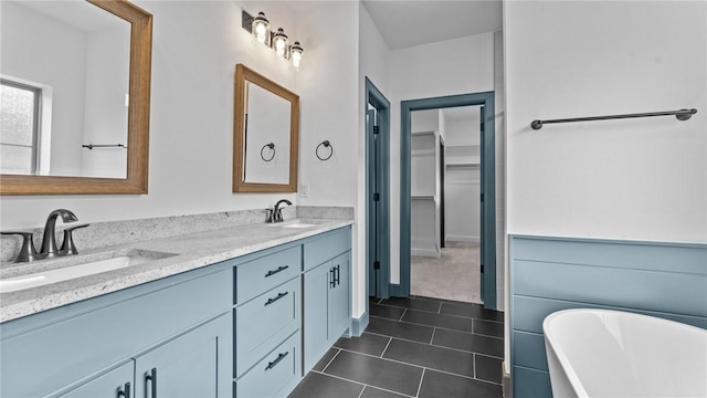 bathroom featuring tile patterned flooring, a washtub, and vanity