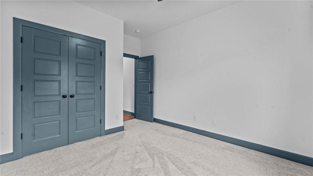 unfurnished bedroom with a closet and light colored carpet