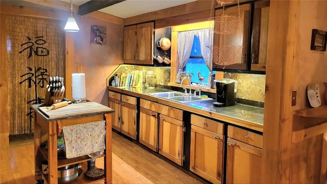 kitchen featuring decorative backsplash, sink, hanging light fixtures, and light hardwood / wood-style flooring