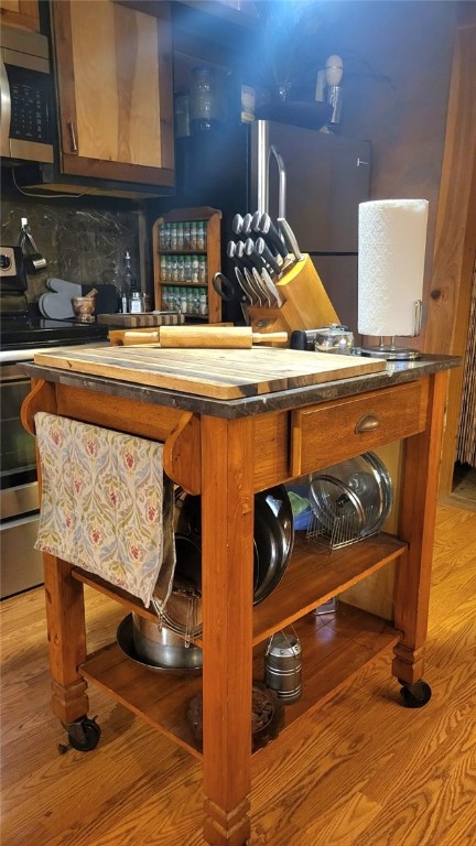 bar featuring decorative backsplash, light wood-type flooring, stainless steel appliances, and butcher block countertops